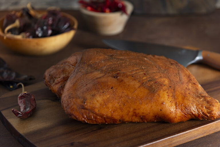 Whole turkey breast on cutting board with bowls of spices in background